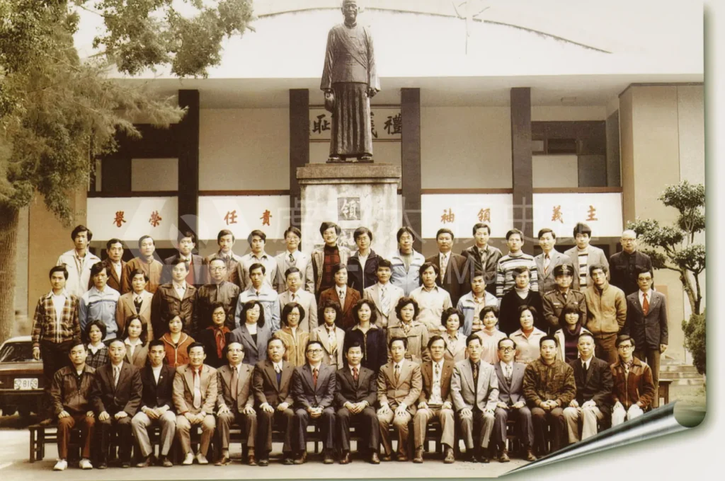 A group of people taking a group photo in front of a bronze statue。