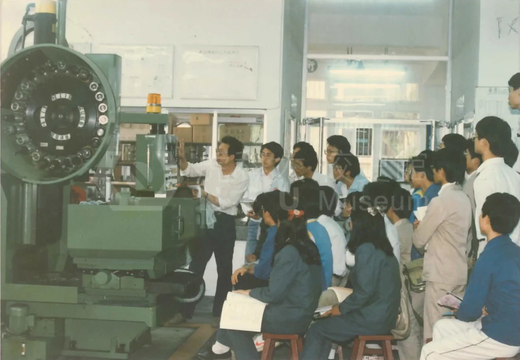 Students observing a teacher operating machinery。