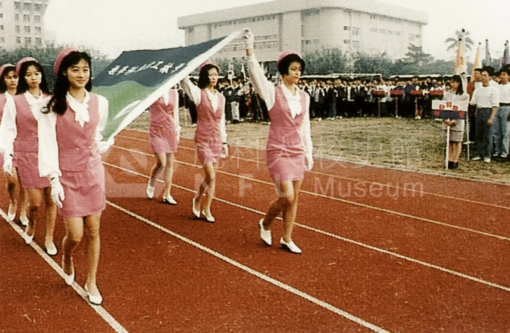 Students line up on the playground，with flag bearers passing in front。